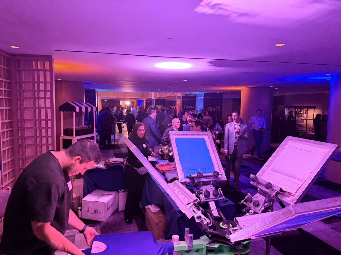 Monogram and print station glowing under violet uplighting during an evening wedding reception